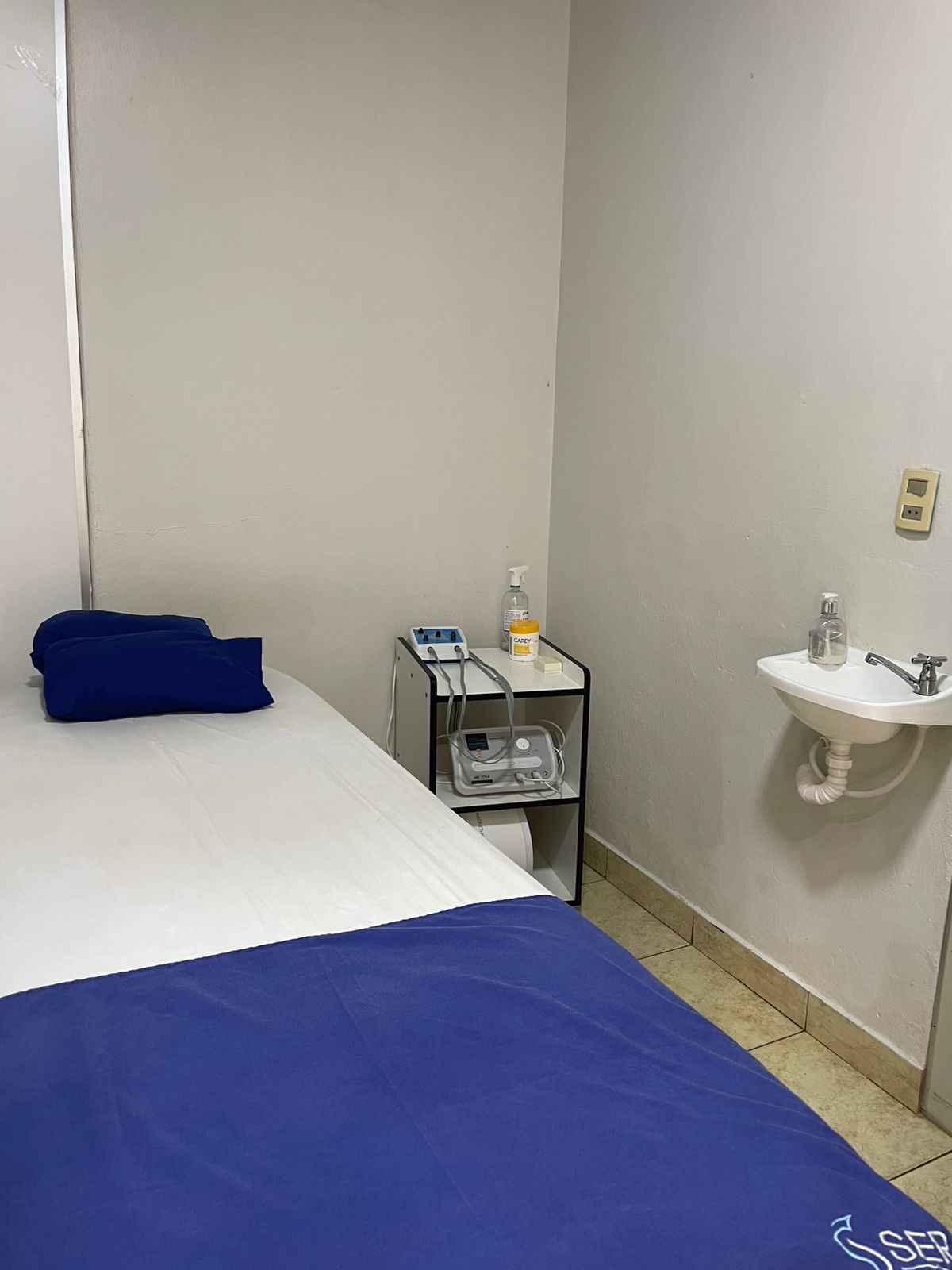 Camilla de tratamiento con equipamiento de fisioterapia y lavamanos